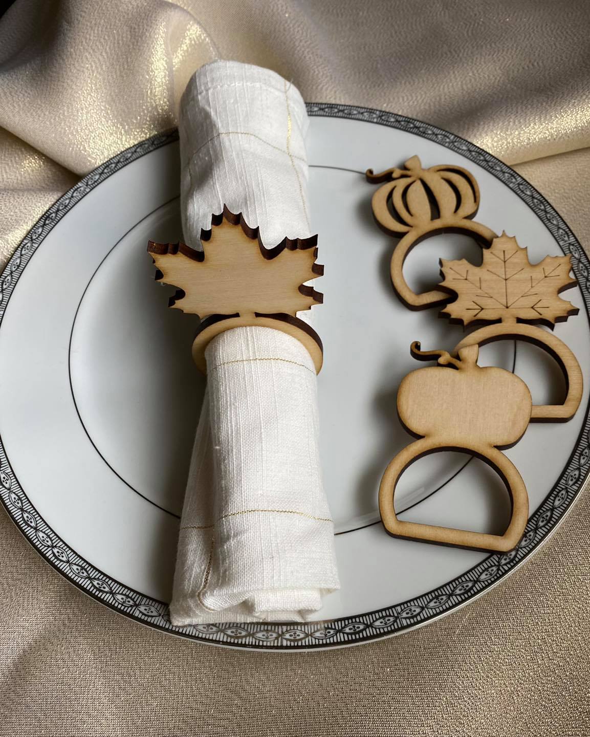 Graceful Creations by Graciela handcrafted wood Thanksgiving napkin rings in maple leaf and pumpkin shapes on a plate
